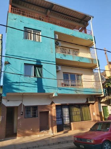 un edificio azul con un coche rojo estacionado frente a él en Habitaciones Villa Blosset en Posadas