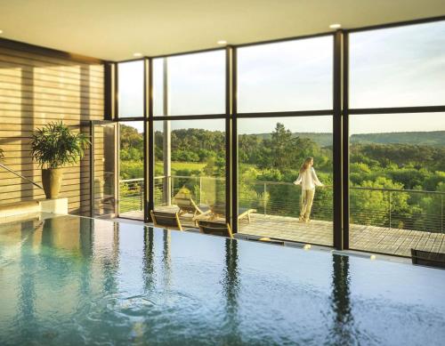 uma casa com uma piscina com vista para as montanhas em La Gree Des Landes - Eco-Hotel-Spa Yves Rocher em Cournon