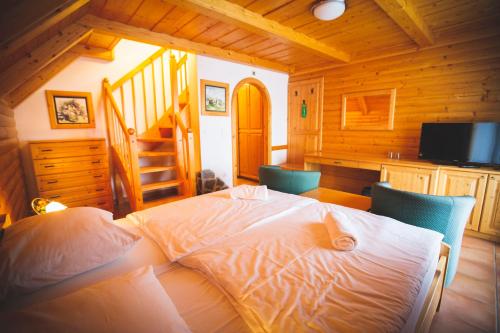 a bedroom with a bed with two chairs and a staircase at Hotel Tisa Pohorje in Pohorje