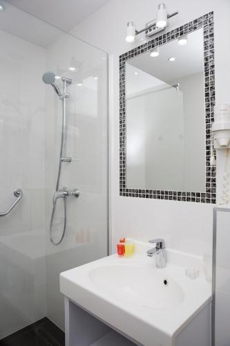 a white bathroom with a sink and a mirror at Hotel Jantar Wellness & Spa in Ustka