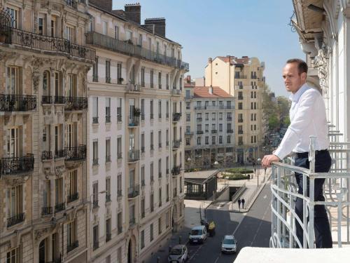 a man standing on the balcony of a building at Grand Hotel des Brotteaux Lyon Ctre - Handwritten Collection in Lyon