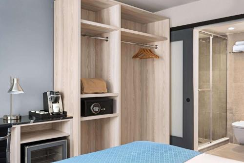 a bedroom with a bed and a bathroom with a shower at Wingate by Wyndham New York Midtown South/5th Ave in New York