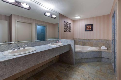 ein Badezimmer mit zwei Waschbecken, einer Badewanne und einem Spiegel in der Unterkunft Baymont by Wyndham Franklin in Franklin