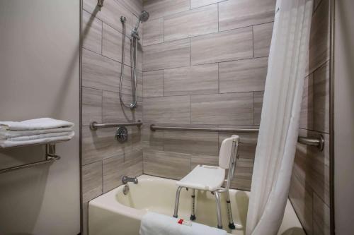 a bathroom with a bath tub and a chair in it at Super 8 by Wyndham St. Louis North in Saint Louis