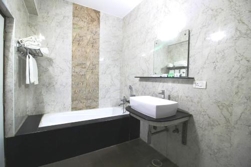 a bathroom with a sink and a bath tub at Saibala Grand Airport Hotel in Chennai
