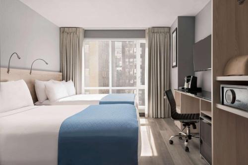 a hotel room with a bed and a desk and a window at Wingate by Wyndham New York Midtown South/5th Ave in New York