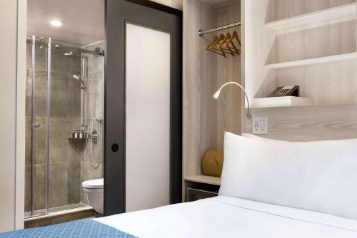 a bathroom with a bed and a shower and a toilet at Wingate by Wyndham New York Midtown South/5th Ave in New York