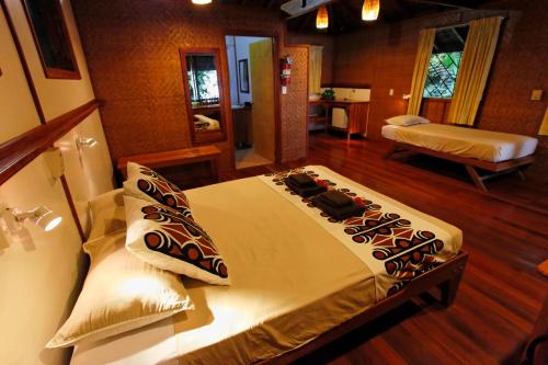A bed or beds in a room at Walindi Plantation Resort