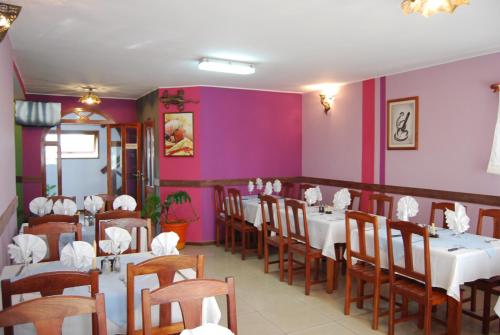 a restaurant with white tables and chairs and purple walls at Antsirabe Hotel in Antsirabe