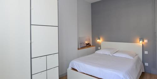 um quarto com uma cama branca e armários brancos em Appart' Anvers em Lyon
