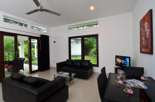 a living room with black couches and a tv at Dream Estate Resort in Senggigi 