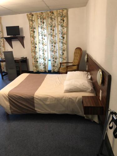 1 dormitorio con cama, silla y cortinas en Hôtel des voyageurs, en Saint-Paulien