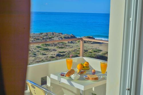 a table with food and drinks on a balcony with the ocean at Falasarna Bay in Falasarna