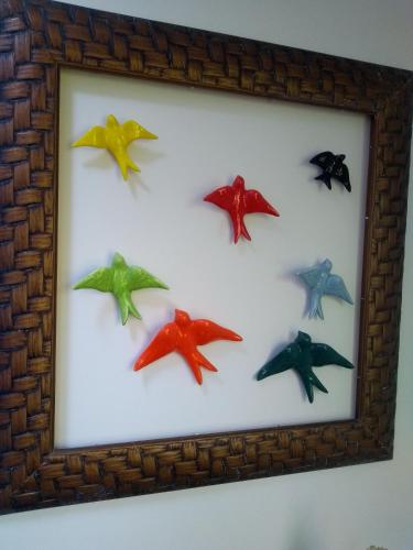 a framed picture of colorful birds on a wall at Solar Lisboa 100 m da Praia com vista para mar in Balneário Camboriú