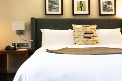 a bed with white sheets and pillows in a bedroom at voco Oxford Thames by IHG in Oxford