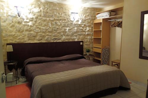 une chambre avec un lit et un mur en pierre dans l'établissement Le Petit Chatelet appartement 3 au coeur de Paris, à Paris