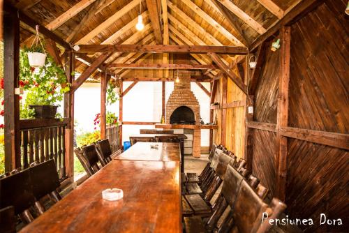 a wooden dining room with a long table and a fireplace at Casa Dora in Moieciu de Sus