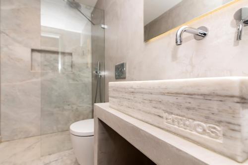 a bathroom with a sink and a toilet and a shower at Lithos Luxury Suites in Tinos Town