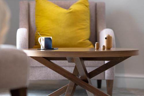 a wooden table with a yellow pillow on a chair at voco Oxford Thames by IHG in Oxford
