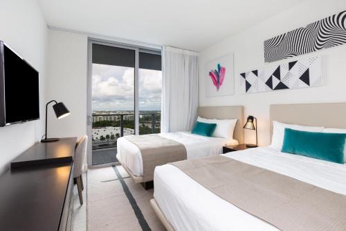 a hotel room with two beds and a window at Ocean Breeze Retreat - Pool Gym Access Views in Hallandale Beach