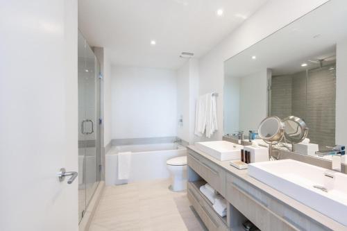 a bathroom with two sinks and a tub and a toilet at Modern 3 bedroom at Hollywood Beach Resort 28th floor in Hallandale Beach