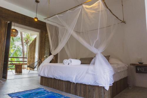 a bedroom with a bed with a mosquito net at Bikini Beach House in Puerto Escondido