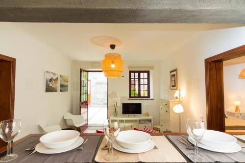ein Esszimmer mit einem Tisch mit Tellern und Weingläsern in der Unterkunft Quinta do Torcaz in Horta