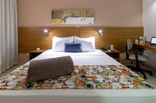 a hotel room with a large bed and a desk at Comfort Hotel Bauru in Bauru