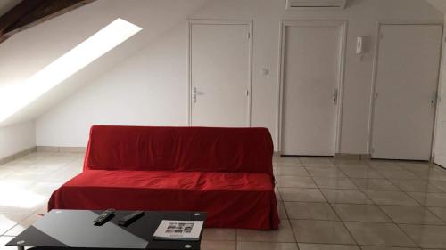 Habitación con cama roja y mesa. en Vichy en Vichy
