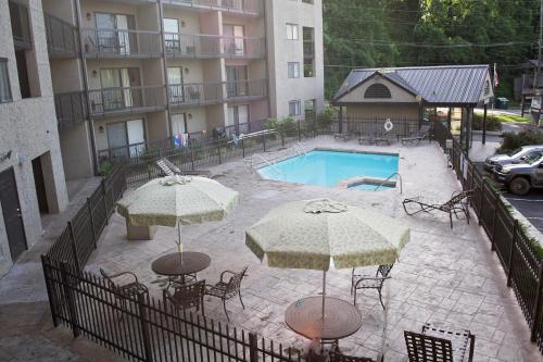 a swimming pool with two umbrellas and chairs at Olde Gatlinburg Rentals in Gatlinburg
