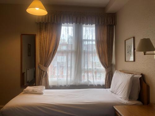 a bedroom with a bed with a large window at Ullswater Hotel in Bournemouth