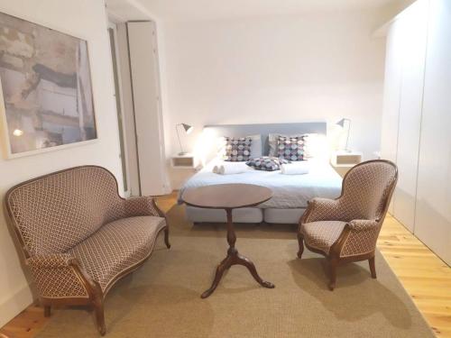 1 Schlafzimmer mit einem Bett, 2 Stühlen und einem Tisch in der Unterkunft Lisbon Combro 77 Charming Studios by Get Your Stay in Lissabon
