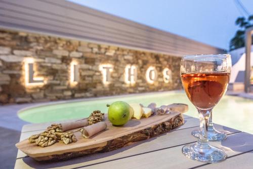a glass of wine sitting on top of a table with food at Lithos Luxury Suites in Tinos Town