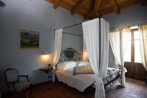 ein Schlafzimmer mit einem Himmelbett und einem Stuhl in der Unterkunft Agriturismo La Torricella in Monforte dʼAlba