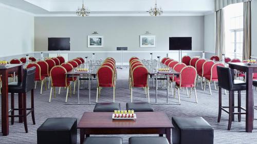 a conference room with red chairs and tables at Hollins Hall Hotel, Golf & Country Club in Bradford