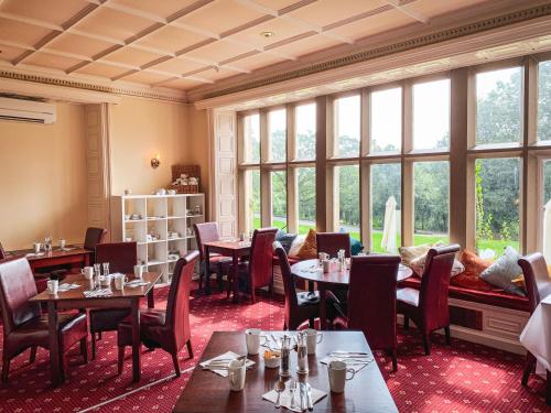 a restaurant with tables and chairs and windows at Hollins Hall Hotel, Golf & Country Club in Bradford