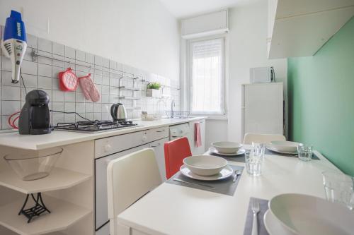eine Küche mit einer weißen Theke und einem Tisch mit Stühlen in der Unterkunft IMHOME - Muratori in Mailand