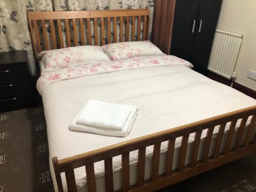 a bed with a wooden frame with a white towel on it at The Guest House in Luton