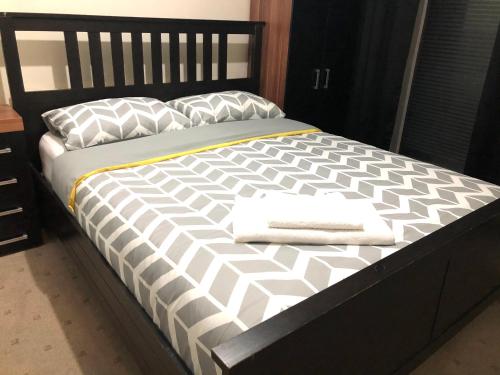 uma cama com um edredão e almofadas preto e branco em The Guest House em Luton