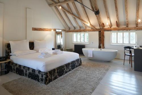 a bedroom with a large bed and a bath tub at Tuddenham Mill Luxury Hotel in Tuddenham