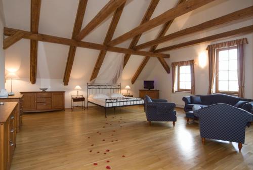 a large room with a bedroom with a bed and chairs at Hotelový a jezdecký areál Dvůr Krutěnice in Krutěnice