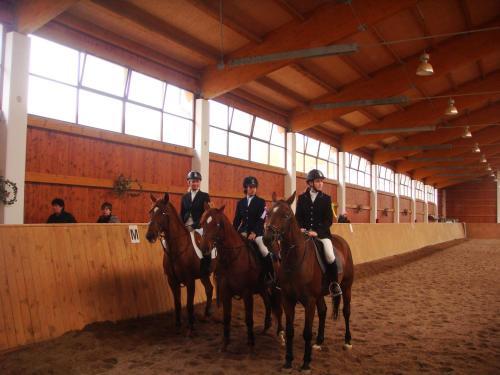 three people in uniform riding horses in a barn at Hotelový a jezdecký areál Dvůr Krutěnice in Krutěnice