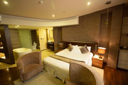 une chambre d'hôtel avec un lit et deux chaises dans l'établissement SG Premium Resort, à Arusha