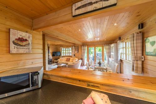 a log cabin living room with a couch and a tv at Pine Log Cabin in Swanage