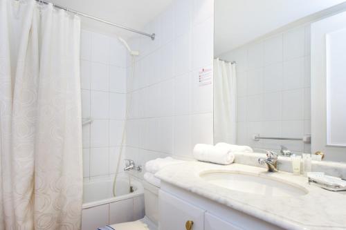 a white bathroom with a sink and a shower at Apart Hotel Cambiaso in Santiago