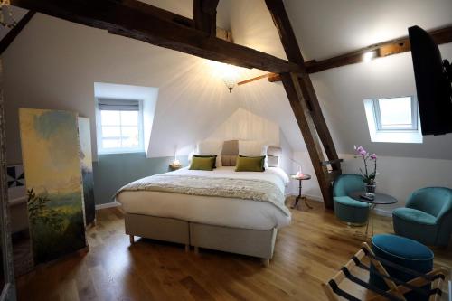 a bedroom with a bed and two blue chairs at Au Jeu de Paume in Épernay