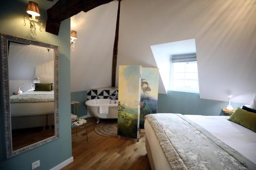 - une chambre avec un lit, un miroir et une baignoire dans l'établissement Au Jeu de Paume, à Épernay