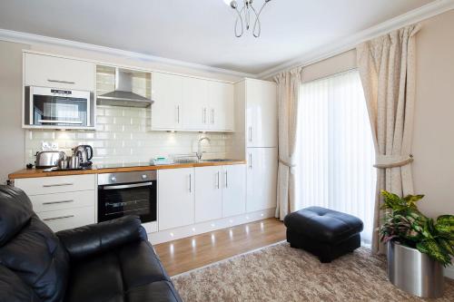 cocina con armarios blancos y sala de estar con sofá en Burbage Holiday Lodge Apartment 5, en Blackpool