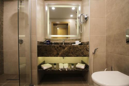 a bathroom with a shower and a toilet and a sink at MENA Tyche Hotel Amman in Amman