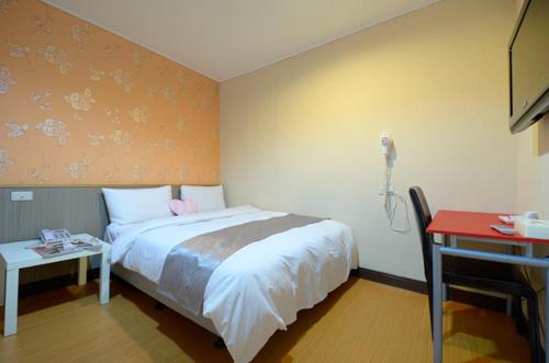 a bedroom with a bed and a phone on the wall at Baoshan Hotel in Zhongli